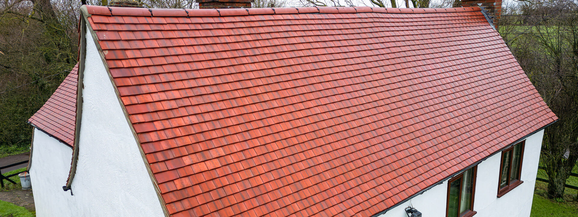 Newly tiled red roof on a rendered home